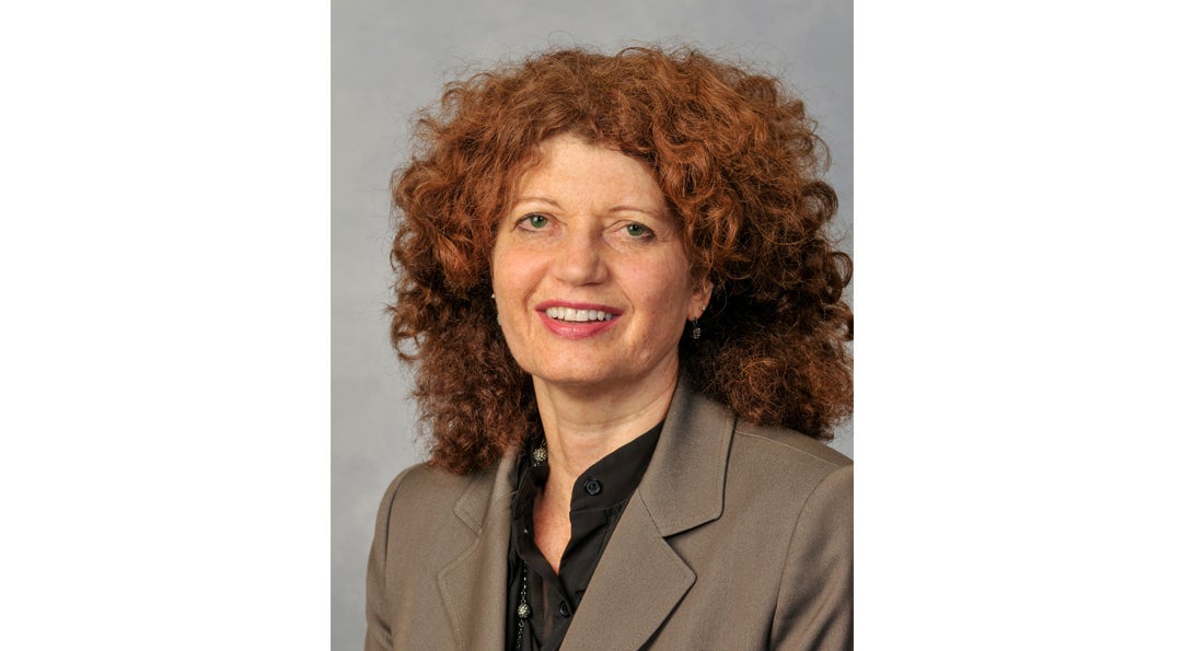 Portrait of Kate Carpenter smiling in brown blazer and black blouse.